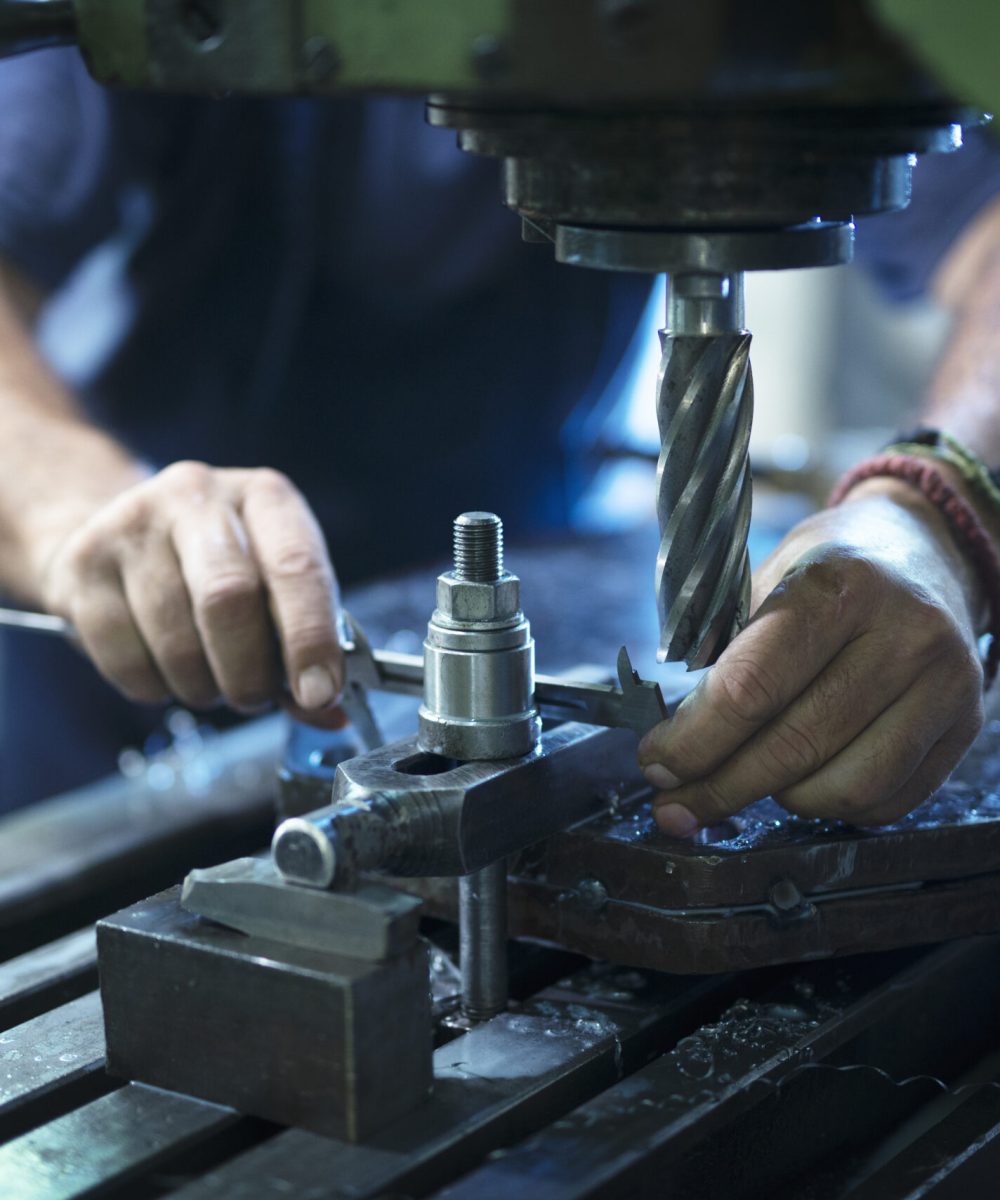 Worker operating industrial machine in metal workshop.